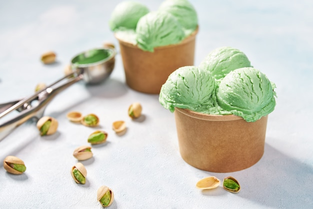 Helado de pistacho en vaso de papel sobre fondo de colores de menta, enfoque selectivo