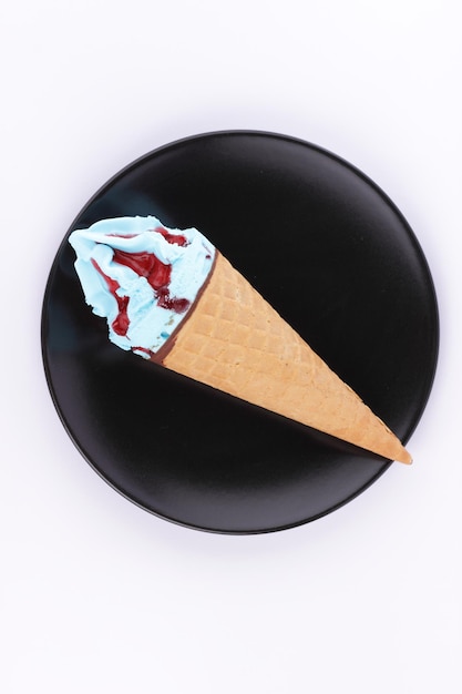 Helado de postre azul y rojo congelado en un cono de galleta en un primer plano de placa negra Cono de helado aislado sobre fondo blanco