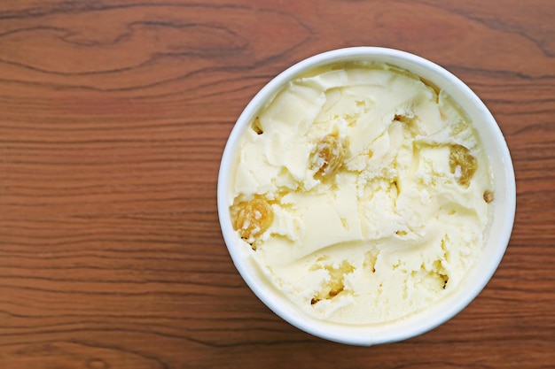 Helado de ron con pasas en una taza sobre una mesa de madera