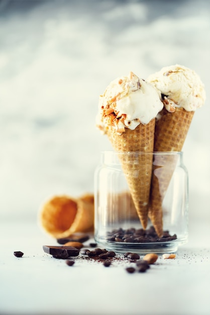 Helado de salsa de caramelo en cono de waffle con granos de café sobre piedra gris