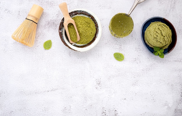 Helado de té verde matcha con cono de galleta y hojas de menta sobre fondo de piedra blanca.