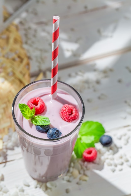 Helado de vainilla con frutos rojos sobre superficie de madera