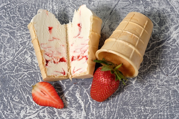 Helado de vainilla en un waffle Copa con relleno de frutas sobre un fondo gris con fresa en un corte