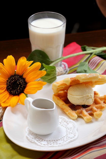 Foto helado de vainilla con waffles y chocolate.