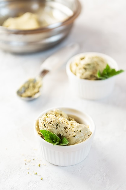 Helado vegano con cáñamo y menta en tazones blancos sobre fondo blanco.