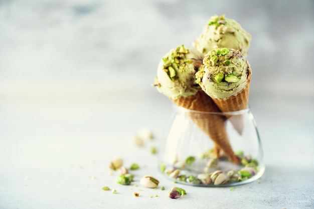 Helado verde en cono de galleta con chocolate y pistachos sobre fondo de piedra gris Espacio de copia del concepto de comida de verano Helado saludable sin gluten