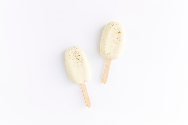 Helados de galleta blanca en un palo sobre fondo blanco. Lay Flat con helados aislados.