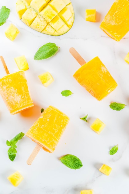 Helados, paletas de hielo. Alimentos dietéticos orgánicos, postres. Batido de mango congelado, con hojas de menta y fruta fresca de mango, sobre una mesa de mármol blanco. vista superior de copyspace