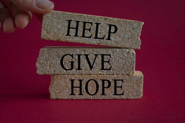 Helfen Sie, Hoffnung zu geben Symbol Konzeptwort Helfen, Hoffnung auf Ziegelsteinblöcken zu geben