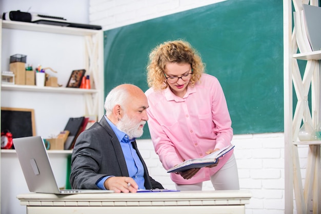 Helfen Sie mir bitte Hausaufgaben überprüfen Schüler fragt Lehrer nach Aufgabe Erzieher und Schüler schauen sich Buch an Erklären schwieriger Informationen Lösen mathematischer Aufgaben Buchquellenwissen Schulbuchkonzept