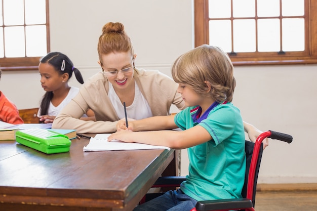 Helfender Schüler des hübschen Lehrers im Klassenzimmer an der Grundschule