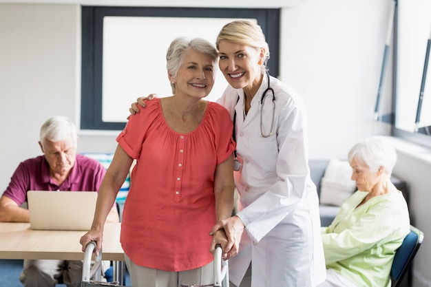 Helfender Senior der Krankenschwester mit Gehhilfe