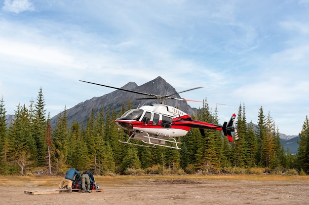 Helicóptero alpino volando y aterrizando en tierra y personal en el parque nacional de Banff, Canmore, Canadá