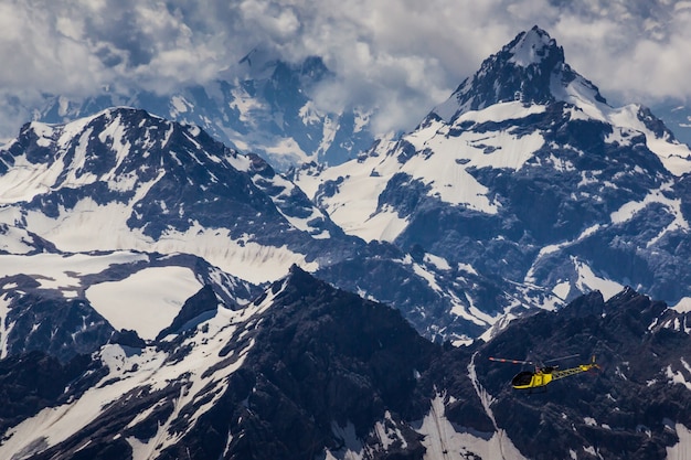 Helicóptero amarillo y montañas nevadas del Cáucaso