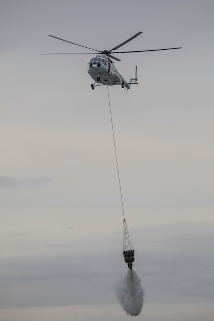 helicóptero apaga un fuego de una canasta de agua