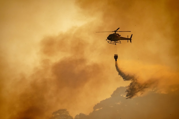 Helicóptero arrojando agua sobre incendios forestales