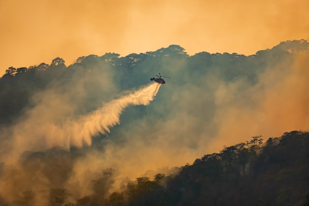 Helicóptero de combate a incêndio lançando água em um incêndio florestal