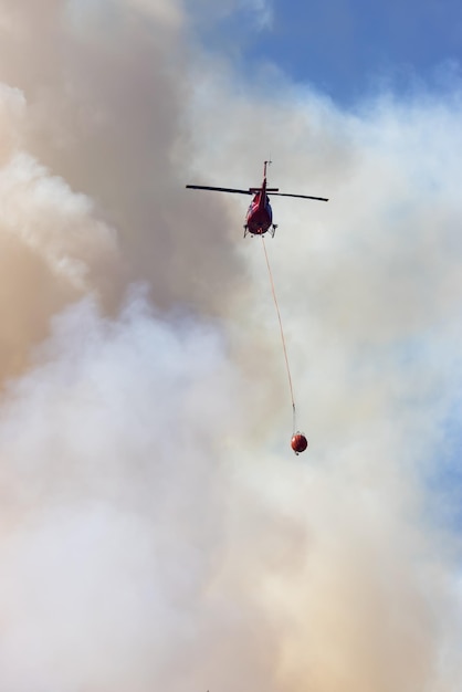 Helicóptero do serviço de incêndios florestais voando sobre incêndios florestais de BC e fumaça na montanha perto de Hope