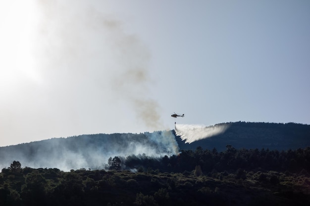 Helicóptero lançando água durante um incêndio florestal