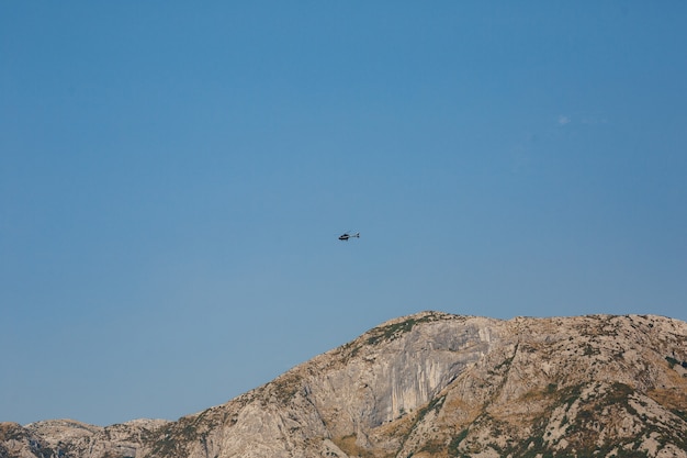 Helicóptero de pasajeros vuela en el cielo azul sobre las montañas