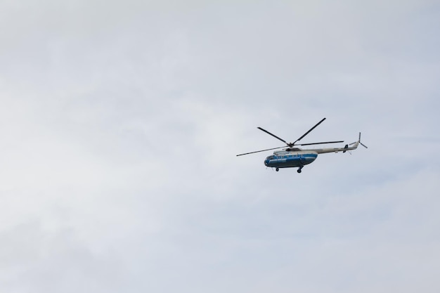 Helicóptero volando alto en el cielo gris disparo de teleobjetivo