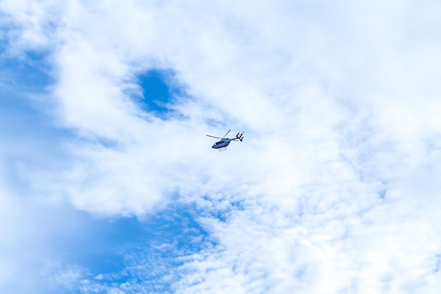 un helicóptero volando en el cielo con un cielo azul y nubes