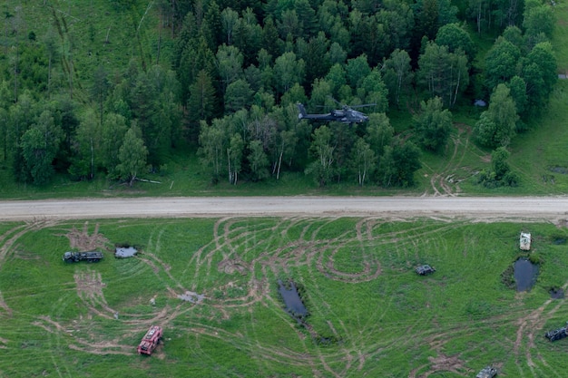 Un helicóptero vuela sobre un camino de tierra y árboles.