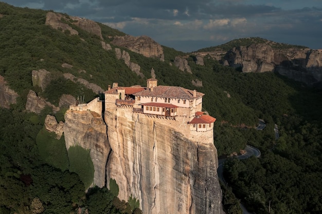 Hell erleuchtetes christliches Kloster auf einer Klippe, umgeben von Bergklippen bei Sonnenuntergang Meteora Griechenland