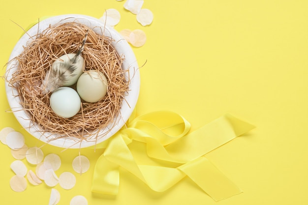 Hellblaue Ostereier im Nest auf gelbem Trendfarbhintergrund. Minimale kreative horizontale Komposition zu Ostern mit Kopierraum. Draufsicht.