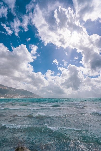 Hellblauer Ozean in einem bewölkten blauen Himmel mit Stadt Vlore am Horizont in Albanien