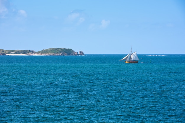 Hellblaues Meer und eine Yacht in der Bretagne, Frankreich