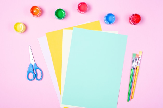 Helle Aquarelle, Pinsel, leeres farbiges Papier auf rosa Hintergrund. Freiraum. Die Schule beginnt mit dem Kunstkonzept