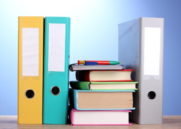 Foto helle büroordner und bücher mit briefpapier auf holztisch auf blauem hintergrund