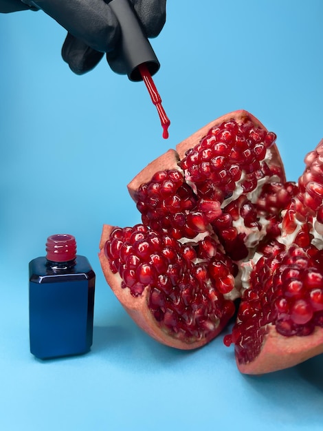 Helle Flasche Nagellack auf blauem Hintergrund mit Granatapfelfrüchten