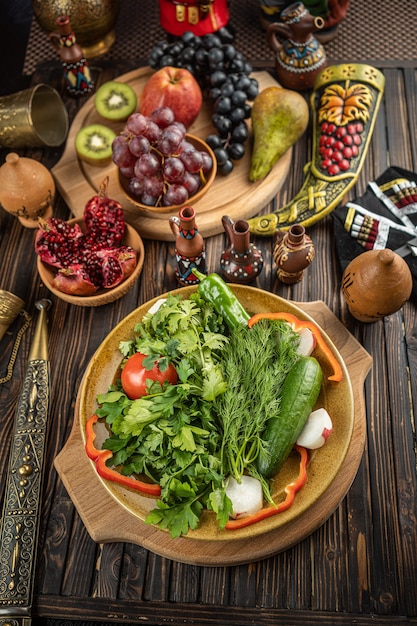 Helle frische grüne salatblätter mit roten tomaten, gurken und rettich in der weißen schüssel auf hölzernem hintergrund. hochwertiges foto