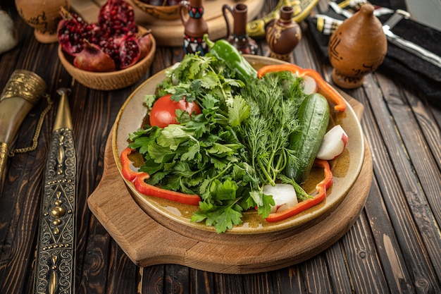 Helle frische grüne Salatblätter mit roten Tomaten, Gurken und Rettich in der weißen Schüssel auf hölzernem Hintergrund. Hochwertiges Foto