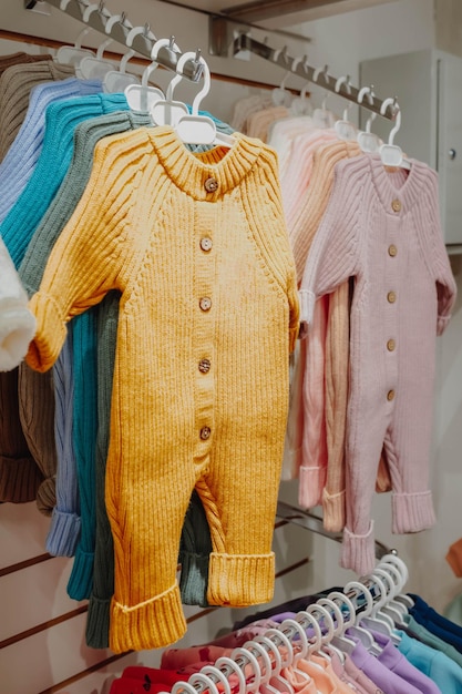 Helle Frühlingsoveralls für Neugeborene hängen in einem Kinderbekleidungsgeschäft auf Kleiderbügeln