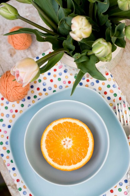 Helle geschnittene Orange liegt auf zwei blauen Tellern. In der Nähe ist eine Gabel und ein alter Notizblock