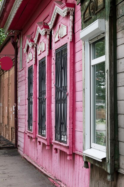 Helle, große, purpurrote Fenster auf einem alten Holzgebäude