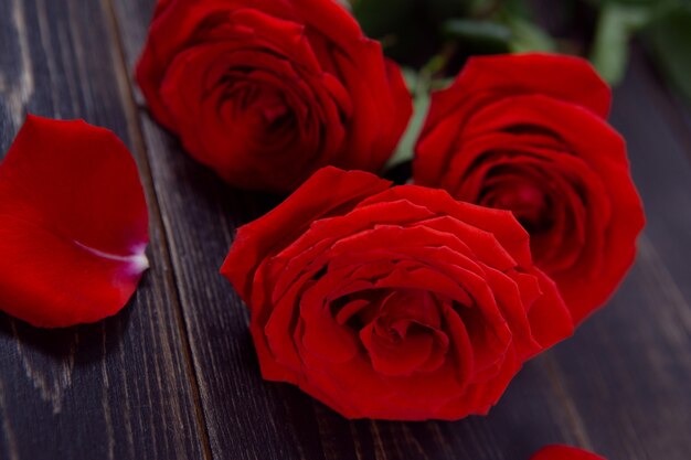 helle große Rosen mit Blütenblättern auf einem dunklen Holztisch