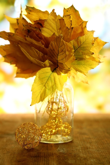 Foto helle herbstblätter in vase auf holztisch auf natürlichem hintergrund