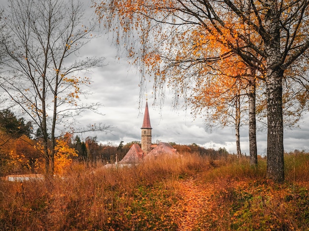 Helle Herbstwolkenlandschaft mit goldenen Bäumen und altem Palast. Gatchina. Russland.
