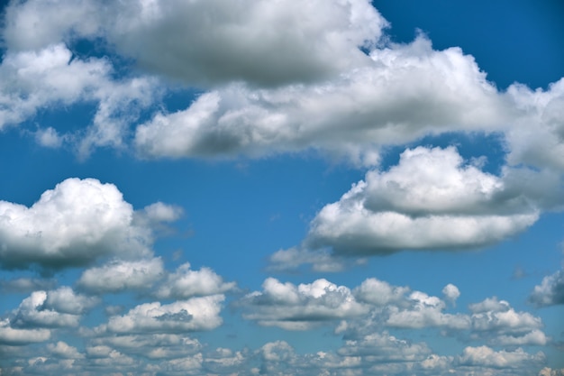 Helle Landschaft aus weißen geschwollenen Kumuluswolken am blauen klaren Himmel.