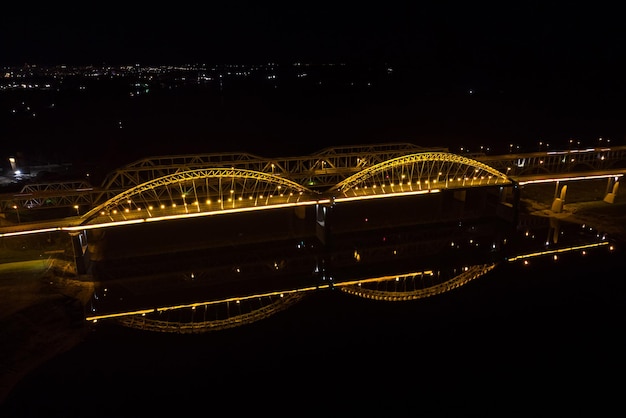 Helle Lichter Brücken mit Bögen Nachtstadt Eine Straßenbrücke über den Fluss, die von einer Drohne aufgenommen wurde