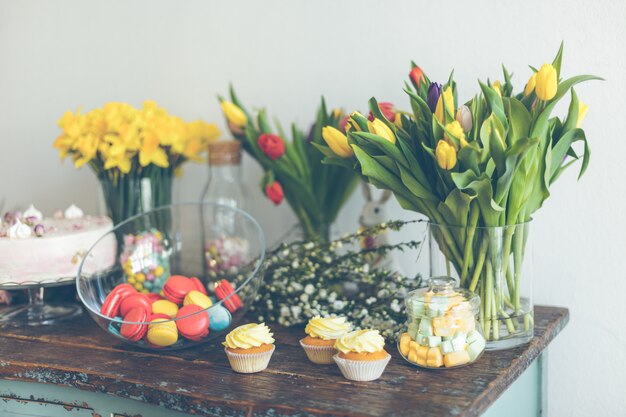 Helle Makronen und Cupcakes auf einem Holztisch