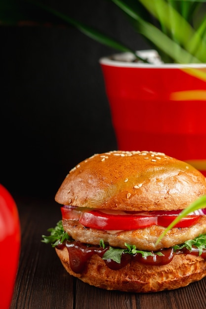 Helle saftige gegrillte Burger mit Grüns und rotem Paprika auf hölzernem Hintergrund. Fast-Food-Konzept