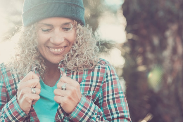 Helle Stimmungsfarben Porträt einer schönen Frau, die lächelt und nach unten schaut - Konzept hübscher weiblicher Menschen, die allein Freizeitaktivitäten im Freien genießen - Natur-Bokeh-Hintergrund