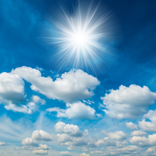 Foto helle strahlende sonne mit weißen, flauschigen wolken am blauen himmel. natur hintergrund