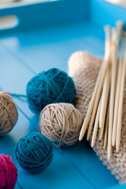 Helle Wollknäuel aus Holz Stricknadeln gestrickte Decke auf blauem Hintergrund liegend