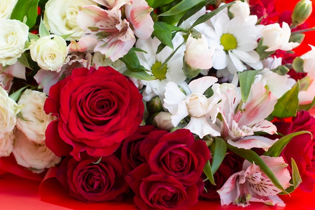 Heller Burgunder und farbige Blumen in einem Blumenstrauß auf einer roten Hintergrundnahaufnahme